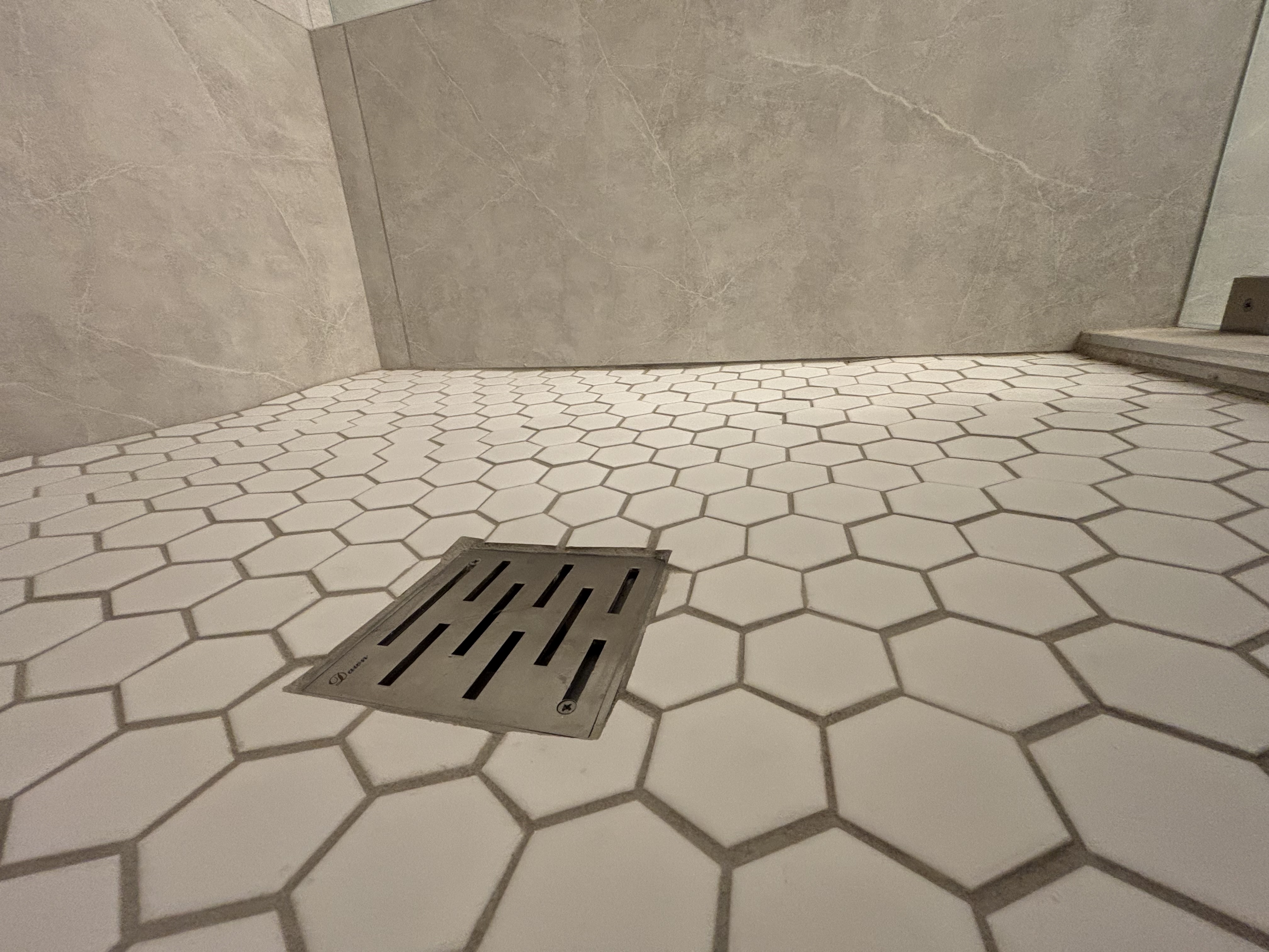 Shower pan viewed from low angle showing uneven slope toward corner